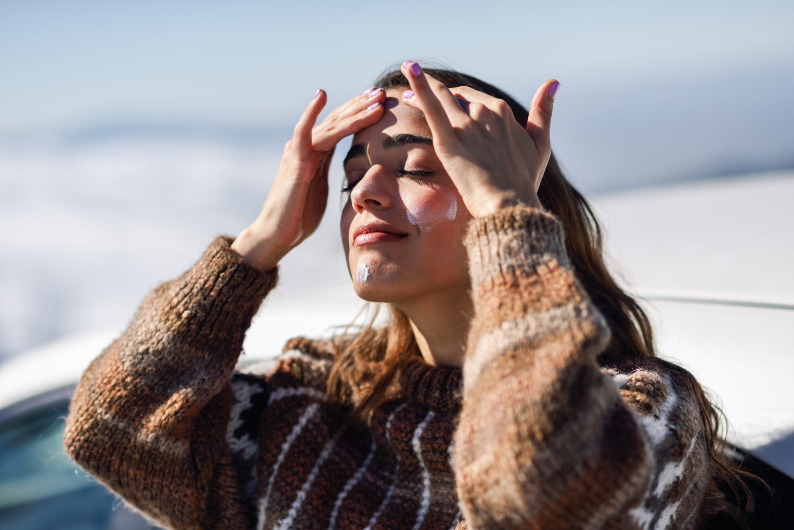 Young woman applying sunscreen